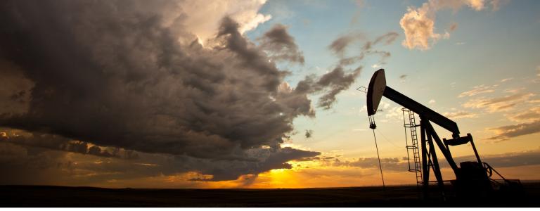 Silhouette of oil pump in prairies against sunset sky