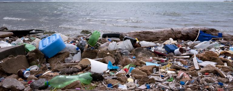 Plastic items litter a beach as a storm cloud rolls in