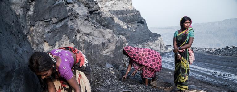 Three women work in a coal mine in traditional Indian dress