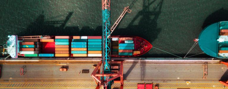An overhead view of a crane and container ship docked at a port
