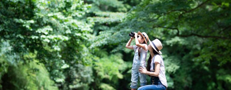 Mother with young daughter looking through binoculars