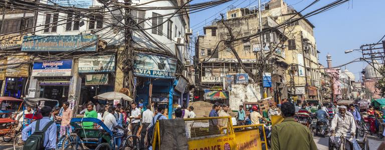 Busy street in a city in India with many electrical cables/wires overhead.