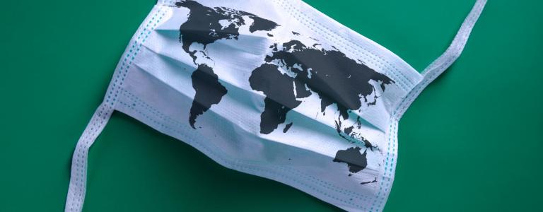 A medical mask with a print of the world map on it against a green background