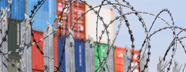 Freight shipping containers behind a fence of barbed razor wire at one of the UK’s business ports in Southampton, Hampshire