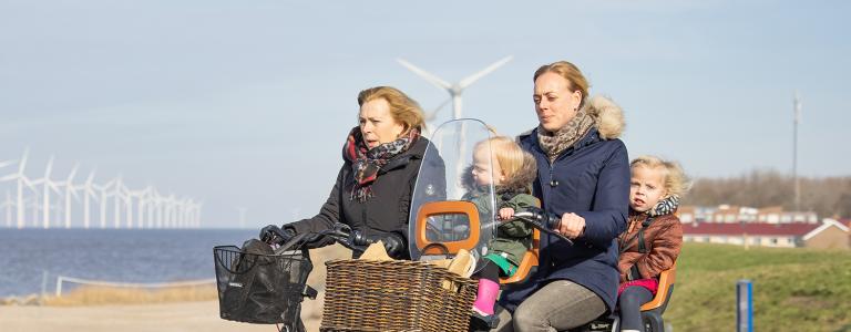  A family cycles past an offshore windfarm in the Netherlands.