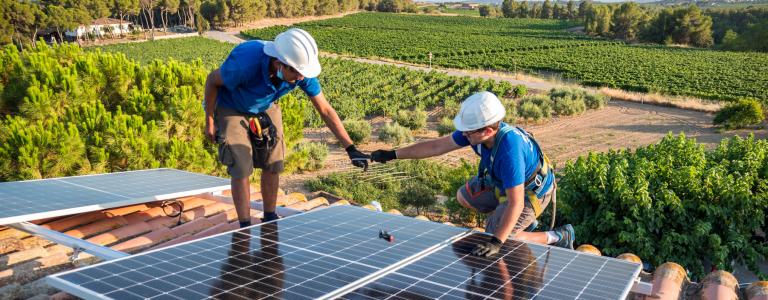 Two technicians adjusting new solar panels on a roof.