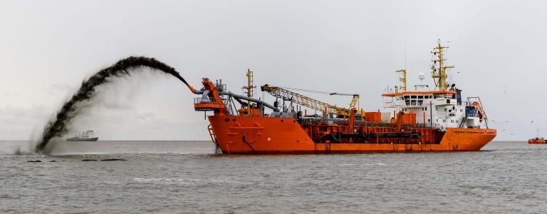 Ship dumping dredged material in ocean