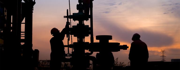 Two oil field workers at sunset.