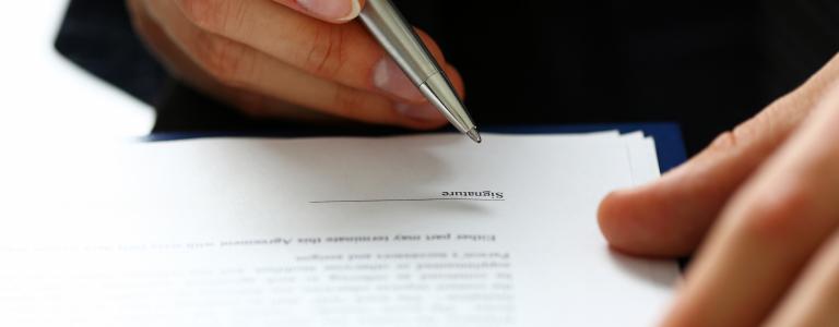 image of male hand signing a contract