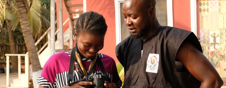 Two people looking at a photograph during Lensational training in Ghana