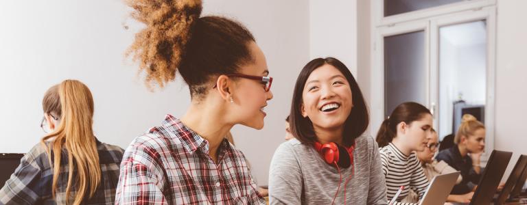 Students in a classroom laughing and having a conversation