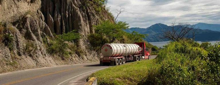 A tank truck drives along a mountain road.