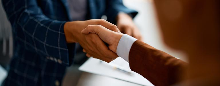 Two business people shake hands in an office.