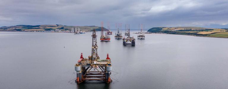 Oil platforms stand offshore.