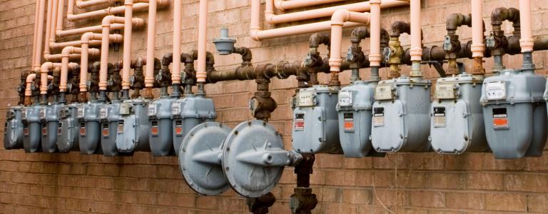 Gas meters line a brick wall