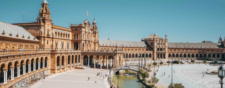 Main square of Seville, water on the foreground and building in the background with a blue sky above