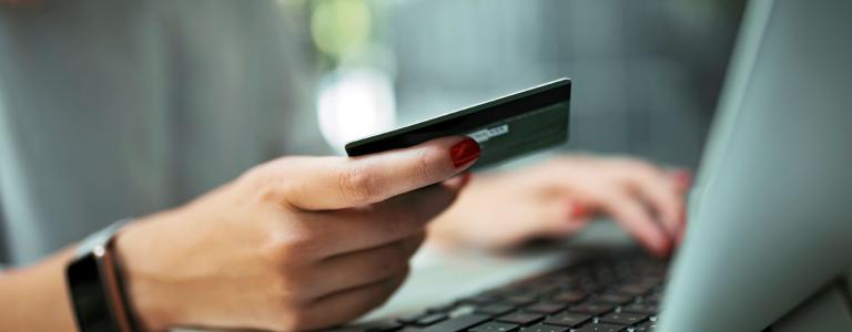 Woman at her computer holding a credit card