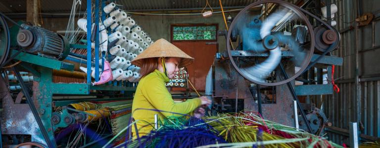 Woman sitting working at a weaving machine