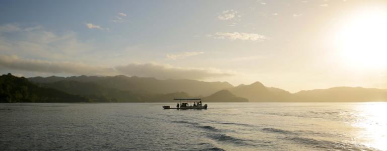 A small fishing boat off an island in Fiji at sunset. 