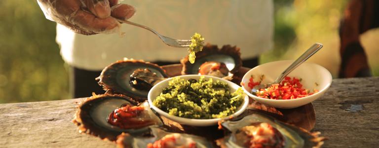 A person plates seafood featuring oyster in Fiji. 