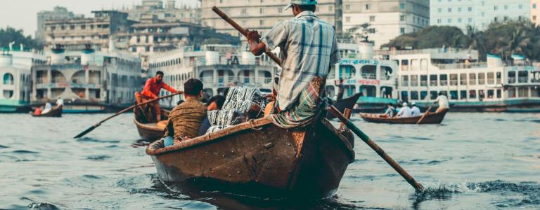 A man riding on brown boat during the day.