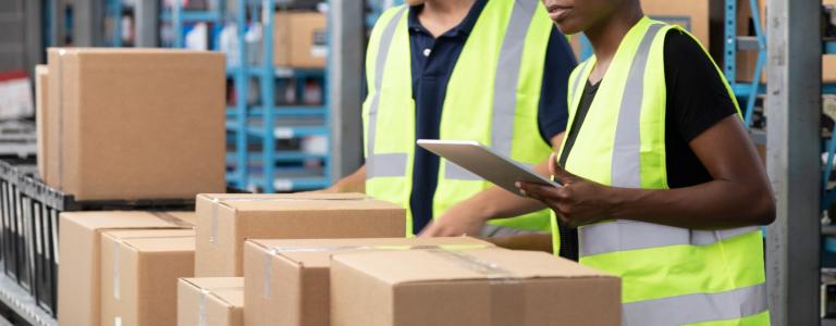 Two workers managing cardboard boxes on a conveyor belt. 