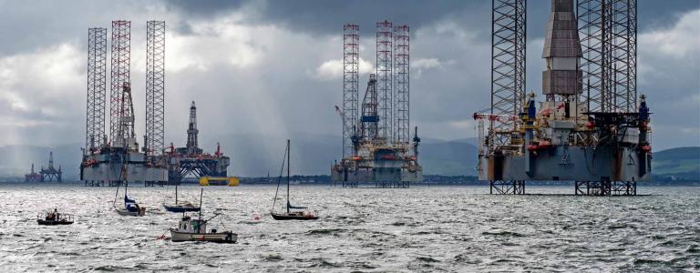 Fishing boats float in front of offshore oil platforms in the North Sea.