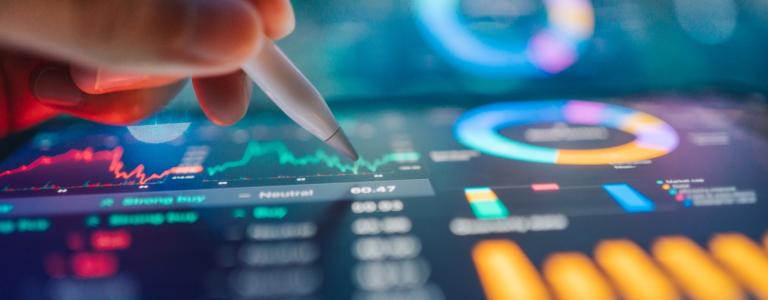 Person writing on a digital screen displaying colourful data.