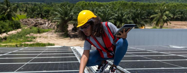 A female worker inspects a solar panel.