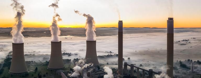 Lethabo Power station seen at sunrise with the smog and mist over the countryside and steam rising from the cooling towers.