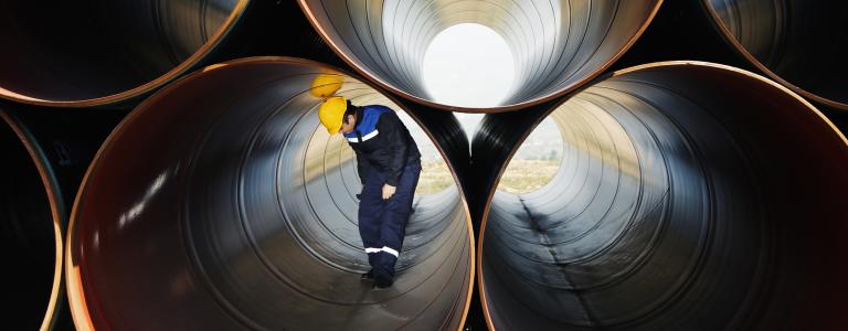 A man standing in a stack of steel pipe.