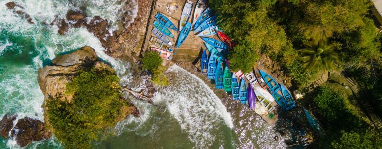 Aerial view of a coast line with colourful boats on the shore.