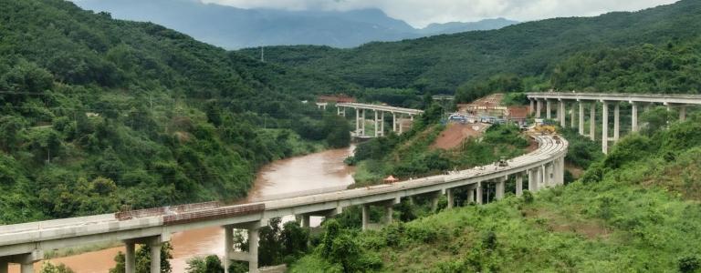 Chinese Xiaomo Highway bridge under construction in the green jungle between Lao border town Boten and Mengla, Yunnan, China.