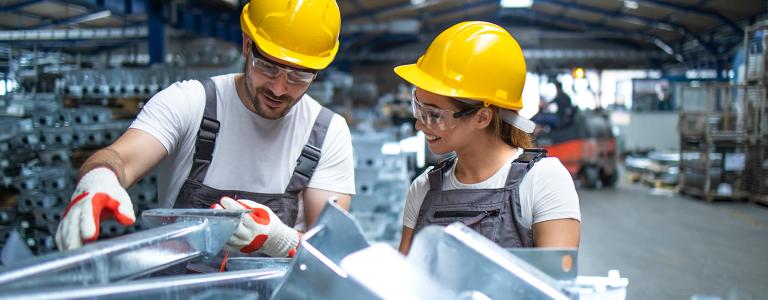 Factory workers inspect metal parts.