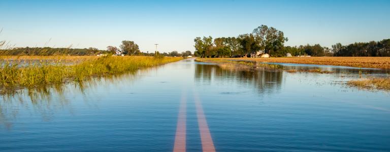 Flooded road with yellow lines on a prairie landscape