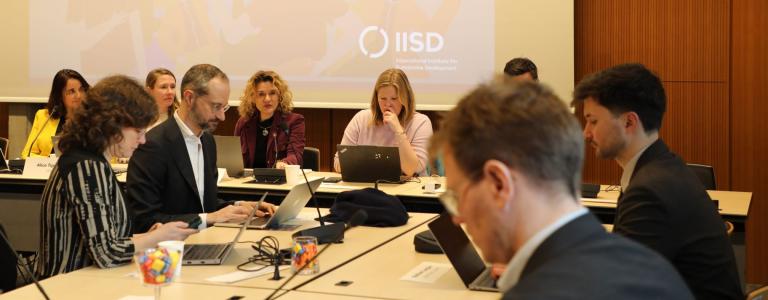 People sitting in a conference room with a presentation in the background.