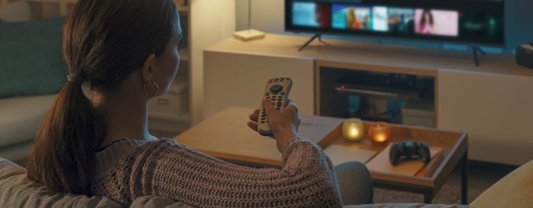 A woman points a remote at a television.