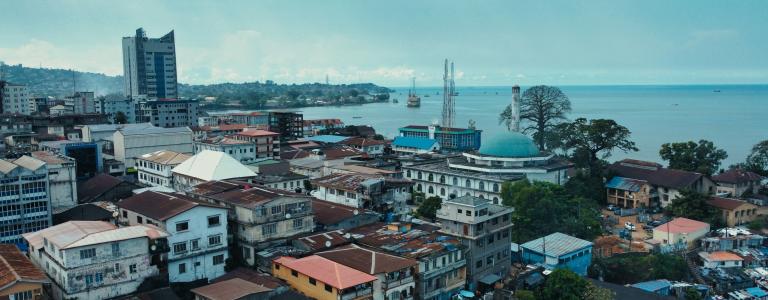 Cityscape of a large city with a mix of low-rise and high-rise buildings, including higher buildings in the background.