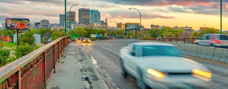 Car crossing bridge in downtown winnipeg at sunset