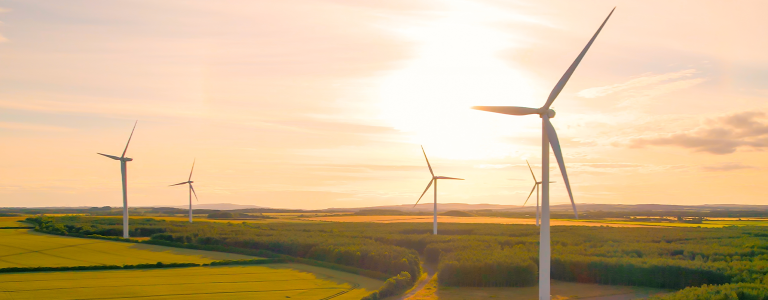 Wind turbines in field against sunset