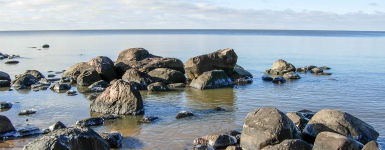 Sandy beach with big rocks and calm waters.