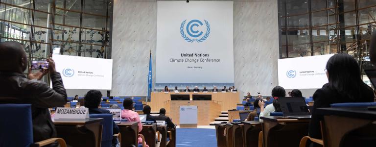 Photo taken down the aisle with people sitting on either side and the UN Climate Change logo at the centre.