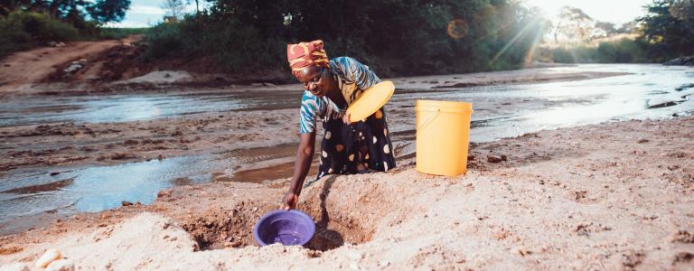 A woman fetches water in a river in Zambia