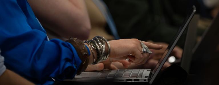 Close up on the hand of a person reading a text on their laptop.