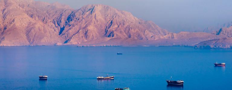 Boats sail over fjords at sunset in Oman.