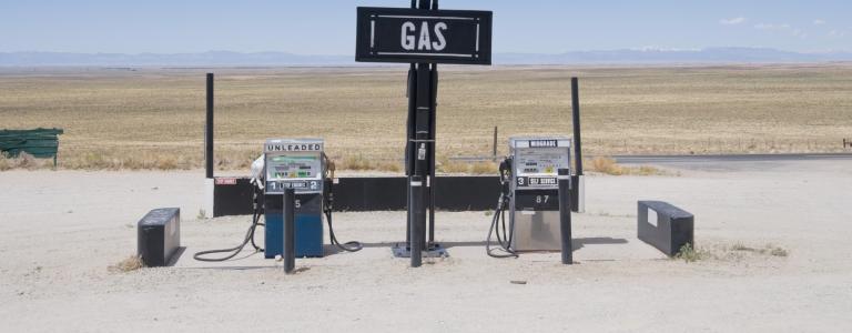 A retro gas station with two fuel pumps in the middle of a desert.
