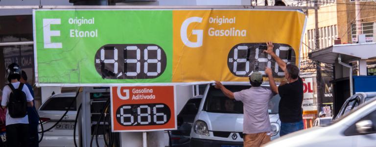 Workers adjust the fuel price sign outside a gas station in Brazil.