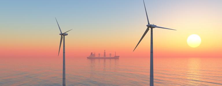 Offshore wind turbines and cargo ship at sunset