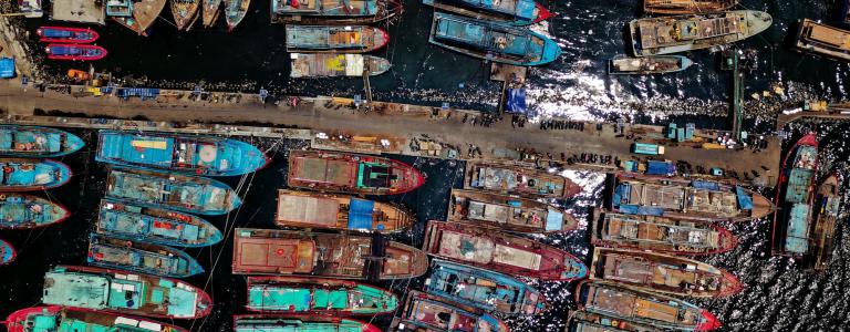 An overhead view of lots of shipping boats crammed together near a dock