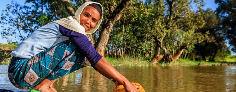 Woman taking water out of a river in Ethiopia.jpg